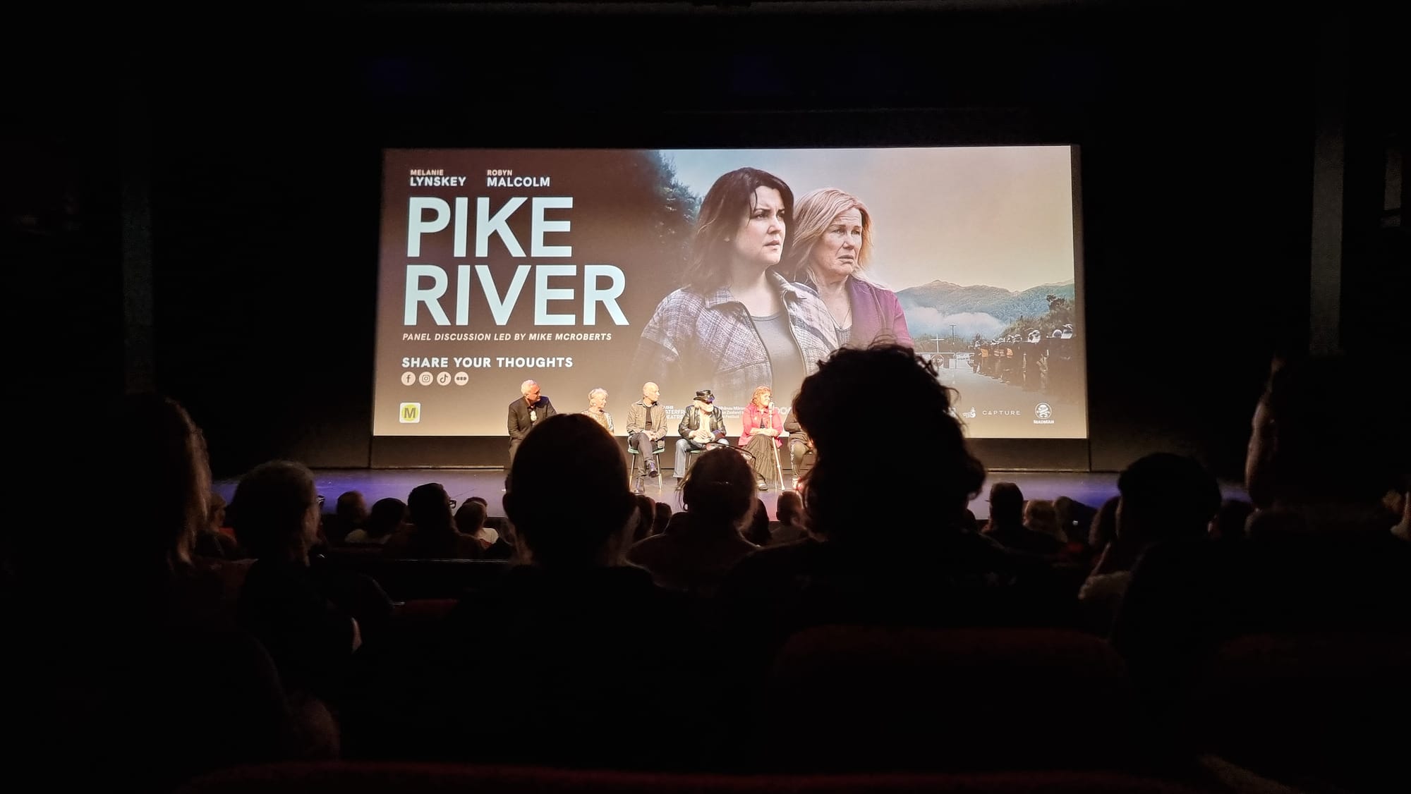 Cinema with still title image of the film projected, the 'in conversation' panel in front