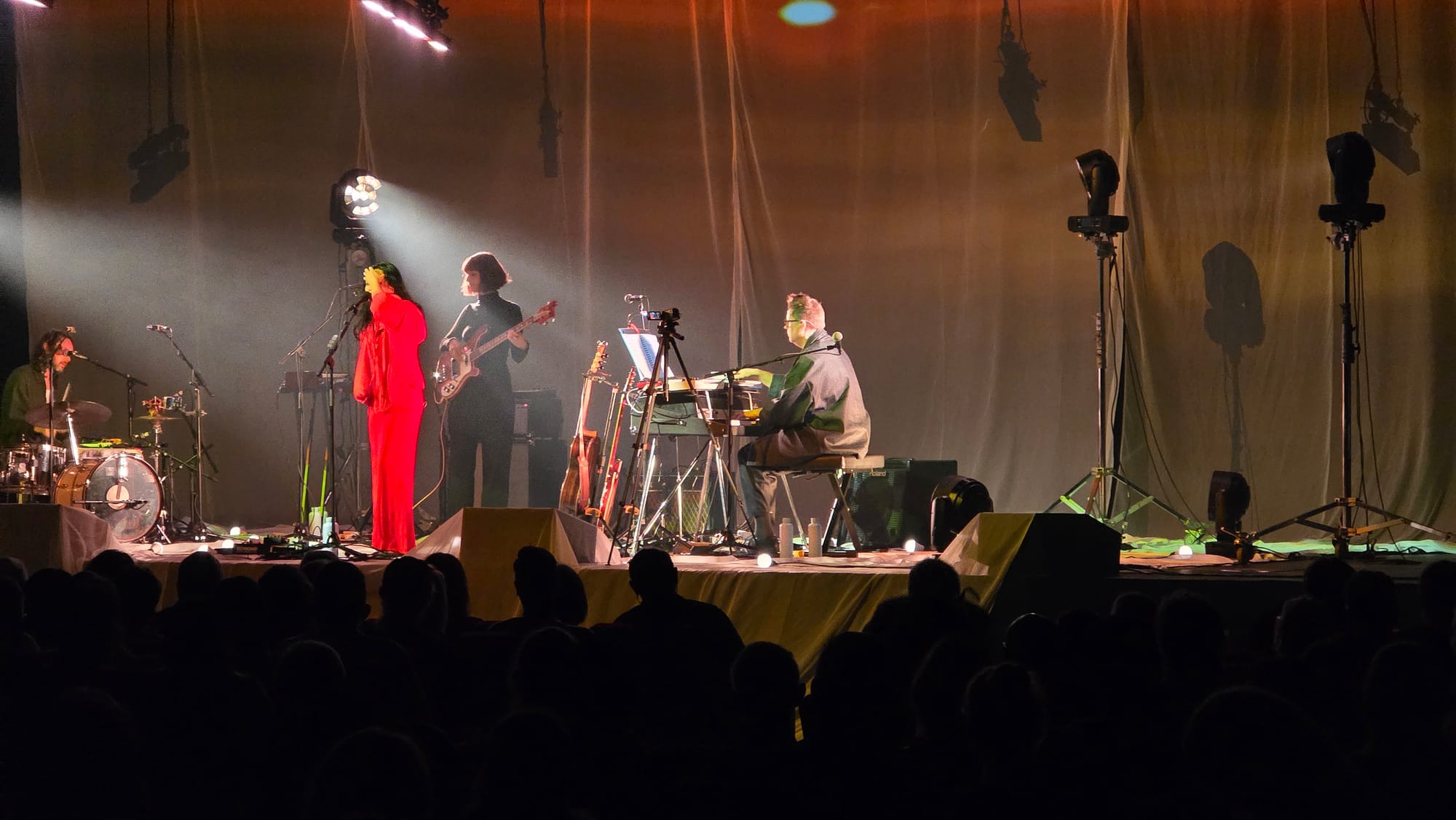 Band on stage, Bic dressed in red suit, singing but holding her hand up gesturing so the only photo I took doesn't show her face